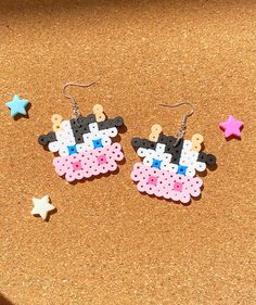 two pairs of earrings made out of plastic beads with stars on the ground next to them