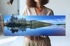 a woman holding up a photograph of a lake