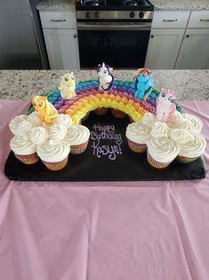 cupcakes with frosting and rainbow decorations on a table