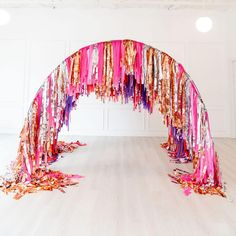 an arch made out of ribbons and streamers in a room with white walls on the floor