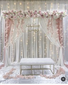 a wedding stage decorated with flowers and white drapes, pink roses on the side