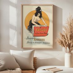 a poster hangs on the wall above a couch in a room with white walls and pillows