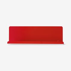 a red shelf sitting on top of a white wall