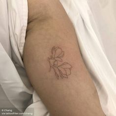 a woman's arm with a small flower tattoo on the left side of her arm