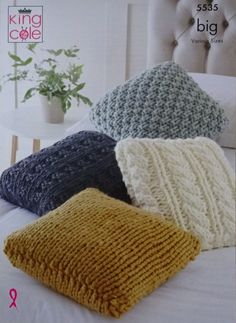 four knitted pillows sitting on top of a bed next to a white headboard