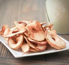 a white plate topped with sliced apple slices next to a glass of milk on top of a wooden table