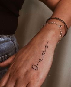 a woman's wrist with the word love tattooed on her left hand, in black ink