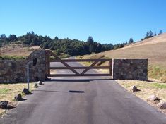 a gated driveway leading to a grassy hill