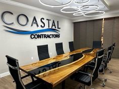 a conference room with black chairs and a wooden table in front of the sign that says coastal