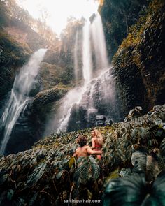 two people sitting in front of a waterfall