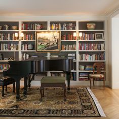 a living room with a piano and bookshelves full of books on the shelves