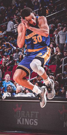 a basketball player is jumping in the air with his foot up to his face while fans look on