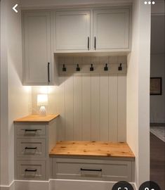 an empty room with white cabinets and wood counter tops on the wall, next to a wooden bench