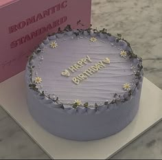 a birthday cake sitting on top of a table next to a pink card and box