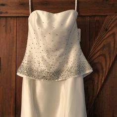 a white dress hanging on a wooden door with silver sequins and beading