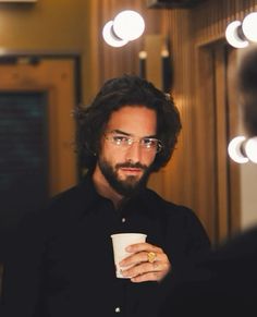 a man with glasses holding a coffee cup