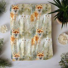 a blanket with an image of a fox on it and other items around it, including plants