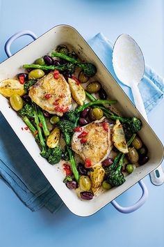 chicken, olives and broccoli in a casserole dish on a blue background