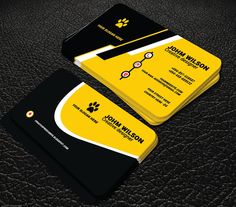 two yellow and black business cards sitting on top of a leather surface, with the logo for