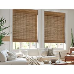 a living room filled with furniture and windows covered in bamboo roman blind shades on the windows