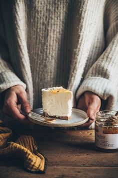 a person holding a plate with a piece of cake on it next to a jar of peanut butter