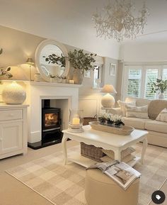 a living room filled with furniture and a fire place under a chandelier in front of a window