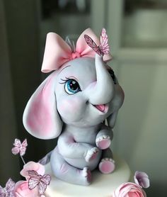 an elephant figurine sitting on top of a cake with pink flowers around it