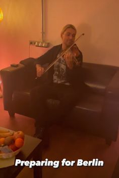 a man sitting on a couch playing the violin