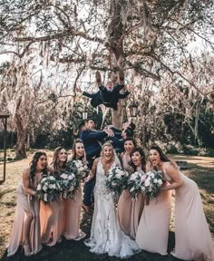 the bride and groom are posing with their bridal party in front of a tree