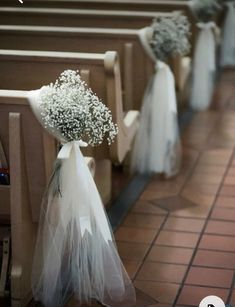 flowers are placed on the pews in this church wedding ceremony aisle line, with white tulle and baby's breath