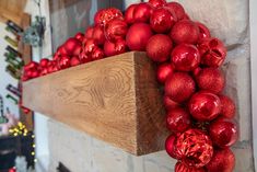 a wooden shelf filled with red ornaments on top of a fireplace