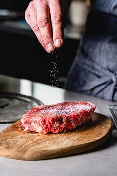 a person sprinkling salt on top of a piece of meat