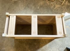 an unfinished wooden shelf sitting on top of a cement floor