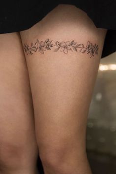 a woman's thigh with flowers on it and the bottom part of her leg