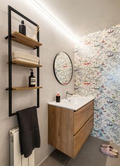 a bathroom with a sink, towel rack and wallpaper on the walls behind it