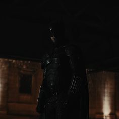 the dark knight is standing in the dark