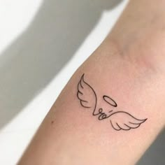 a small tattoo on the arm of a person with an angel wing and two hearts