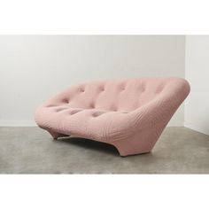 a pink couch sitting on top of a cement floor next to a white wall in a room