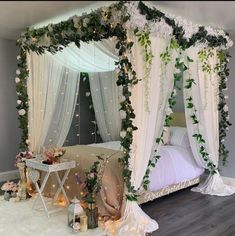 a canopy bed with white flowers and greenery on the top is surrounded by candles