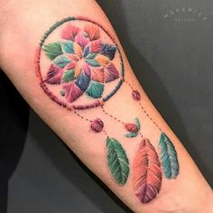 a colorful tattoo on the arm of a woman's leg with leaves and beads