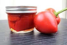 two tomatoes and a jar of tomato jam on a table