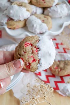 a hand holding up a cookie with white frosting and candy canes