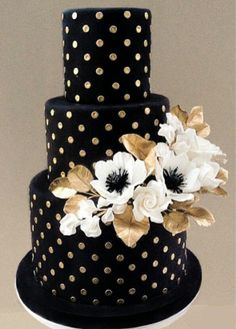 a black and gold polka dot cake with white flowers