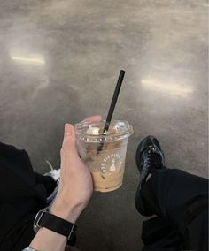 a person holding a drink in their hand with a black straw sticking out of it