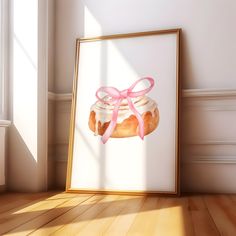 a framed photo with a pink ribbon on it next to a cupcake in front of a window