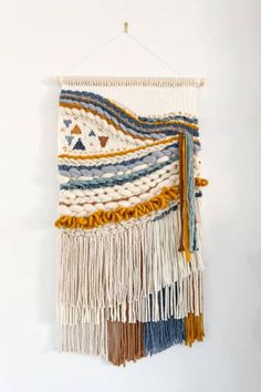 a white wall hanging with multi colored tassels