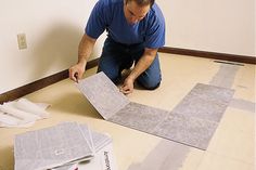 a man sitting on the floor working on some tile