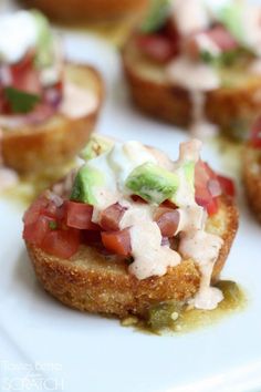 small appetizers with various toppings on a white plate, ready to be eaten