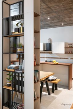 an open kitchen and dining room area with shelving unit in the center, next to a wooden table