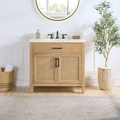 a bathroom vanity with two sinks and a round mirror above it, next to a potted plant